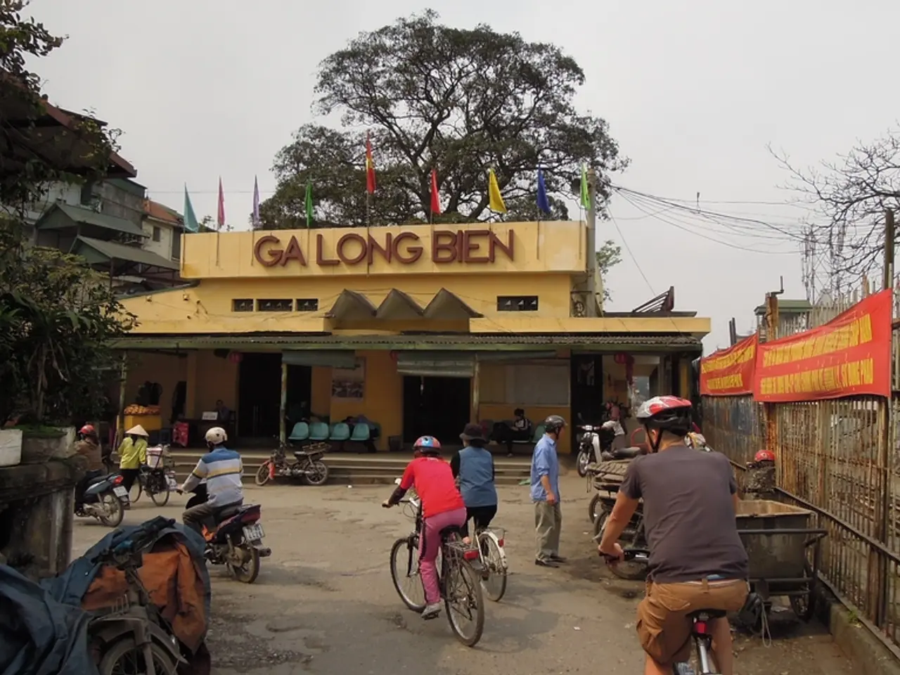 People are passing by a building on cycles and few bikes.