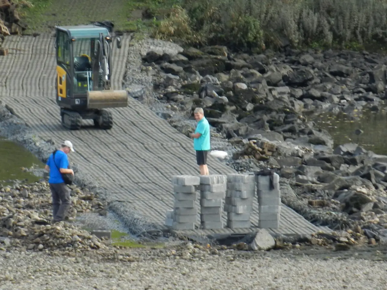 In this picture we can see there are people standing on the under construction road, behind them...