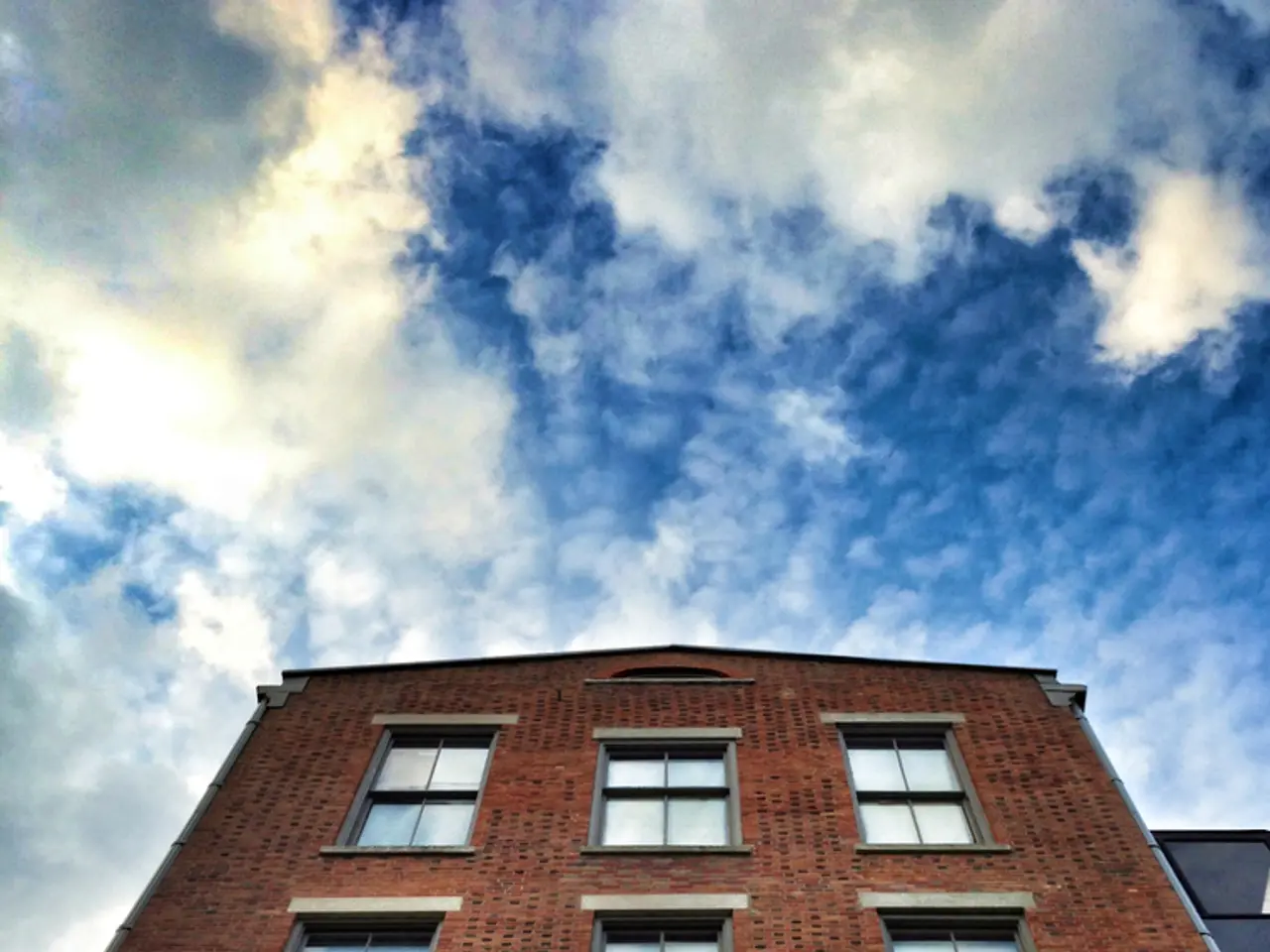 This picture shows about the big brown color building with many glass windows seen in the middle of...