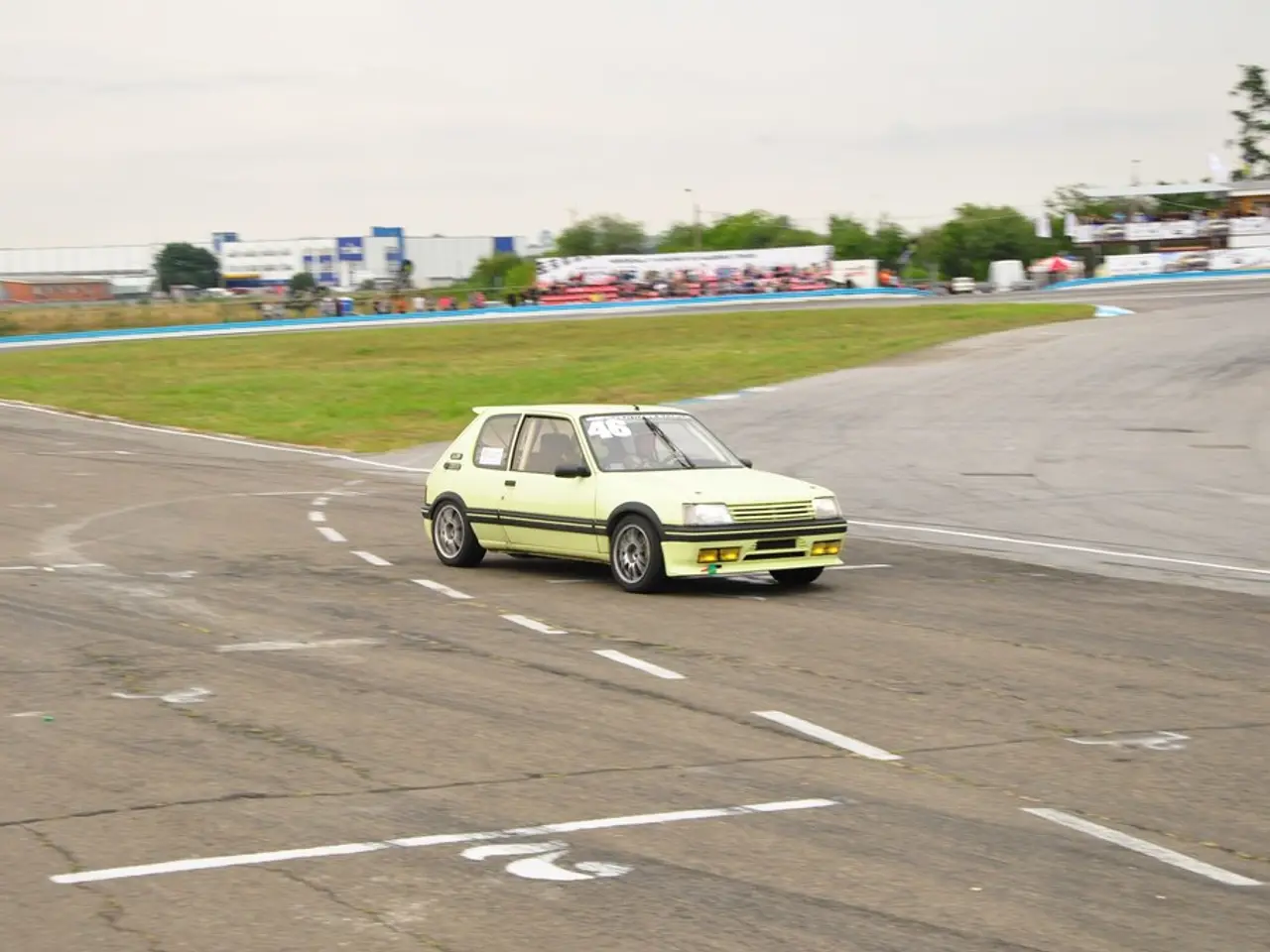 It is a car which is moving on the road, it is in green color, there are buildings in the long back...