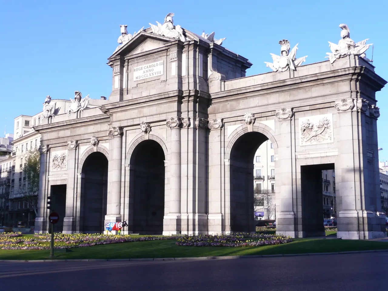 In this image in the center there are some buildings and some sculptures. At the bottom there is...