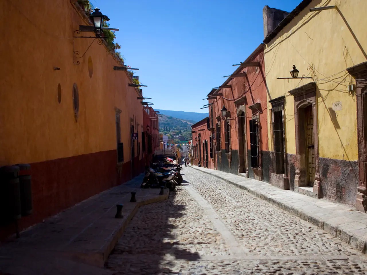 In this image there is a empty road where so many bikes are parked, beside that there are so many...
