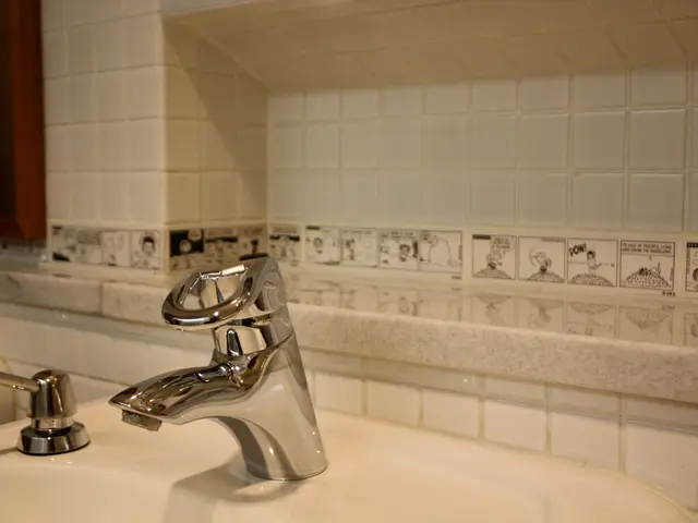 In this image there are tapes on the sink, behind the taps there is a window on the tile wall.
