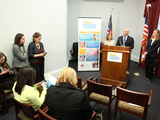 In this picture we can see three women sitting on chairs, in the middle we can see one man and one...