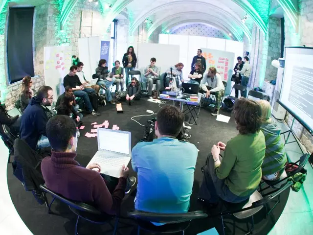 In this picture we can see many people sitting on the chairs and working in front of a projector...