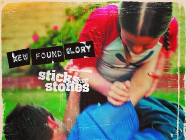 In the image two people are doing fighting. Behind them there is grass and there are some logos.